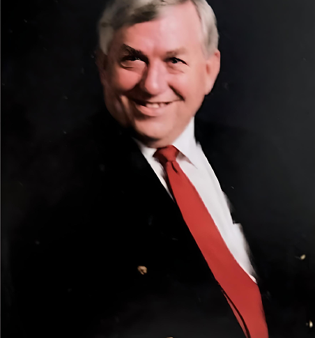 Portrait of our founder, Frank Todd smiling in a black suit and red tie